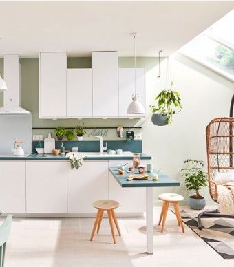 Projeto de cozinha em estilo nature, com móveis de cozinha brancos e com tons azuis, composta por exaustor e armários, assim como plantas decorativas suspensas